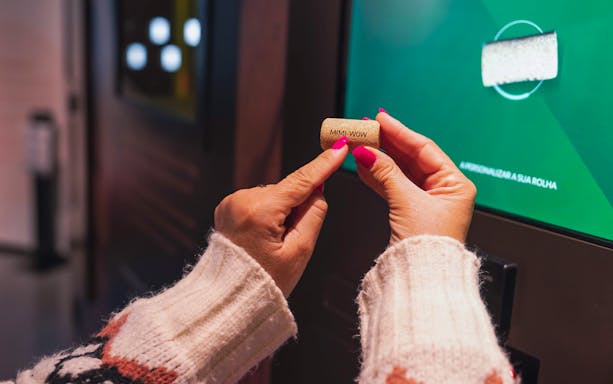 Hands holding a cork with "MMI WOW" at Planet Cork exhibit.