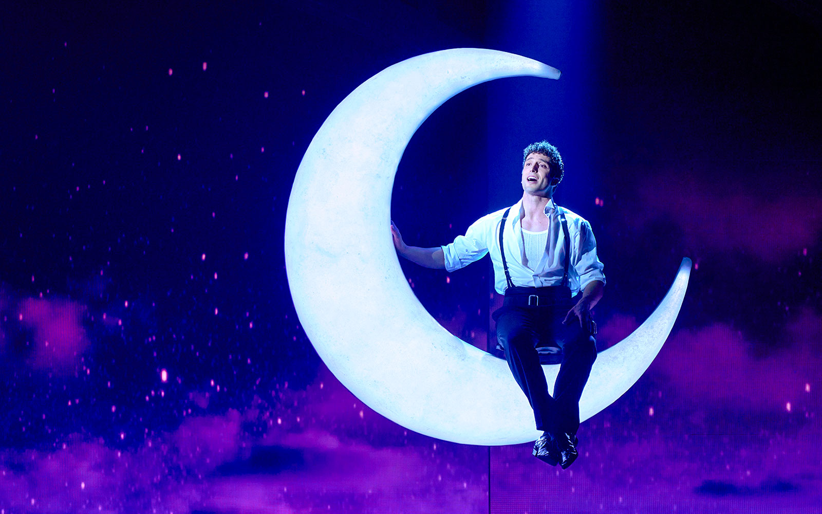 Performer on crescent moon during Cinderella stage show in Madrid.