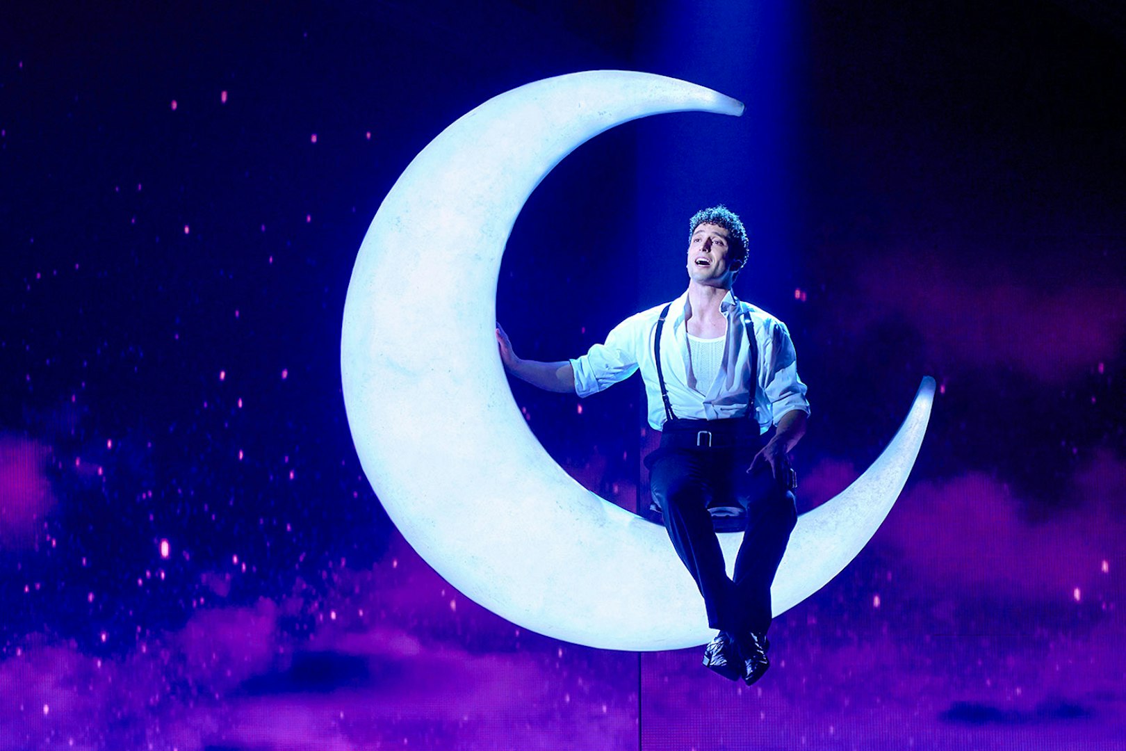 Performer on crescent moon during Cinderella stage show in Madrid.