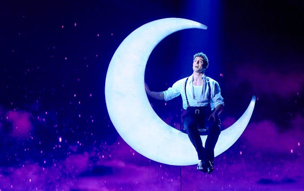 Performer on crescent moon during Cinderella stage show in Madrid.