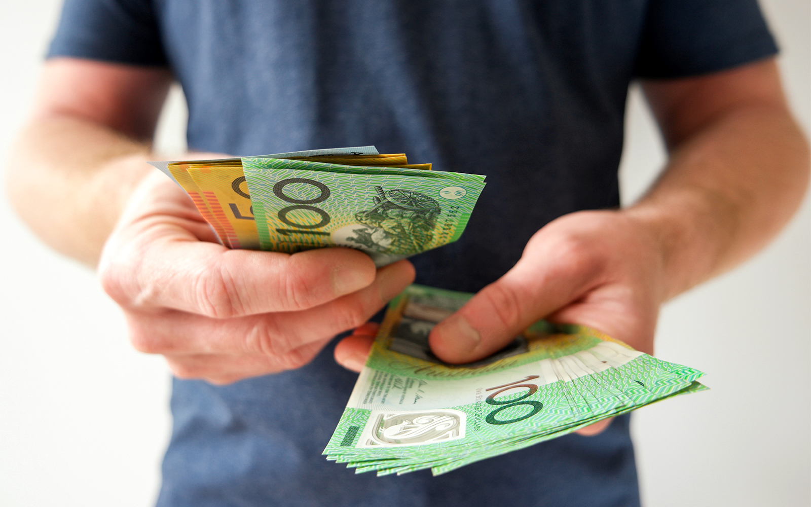 Man counting Australian dollar bills in hand.