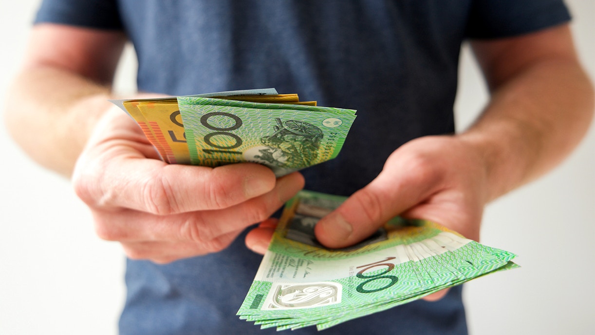 Man counting Australian dollar bills in hand.