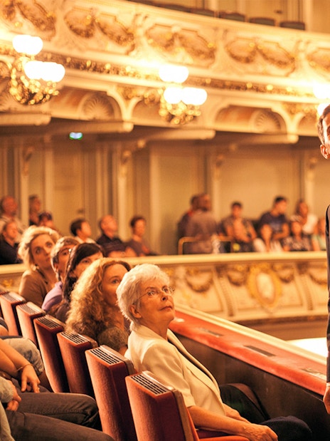 Tour guide leading a group through the ornate interior of the Semperoper in Dresden.