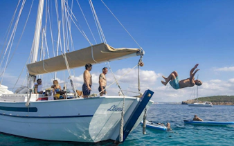 Tourists enjoying a private sunset cruise on a classic boat in Ibiza, with one person diving into the sea.