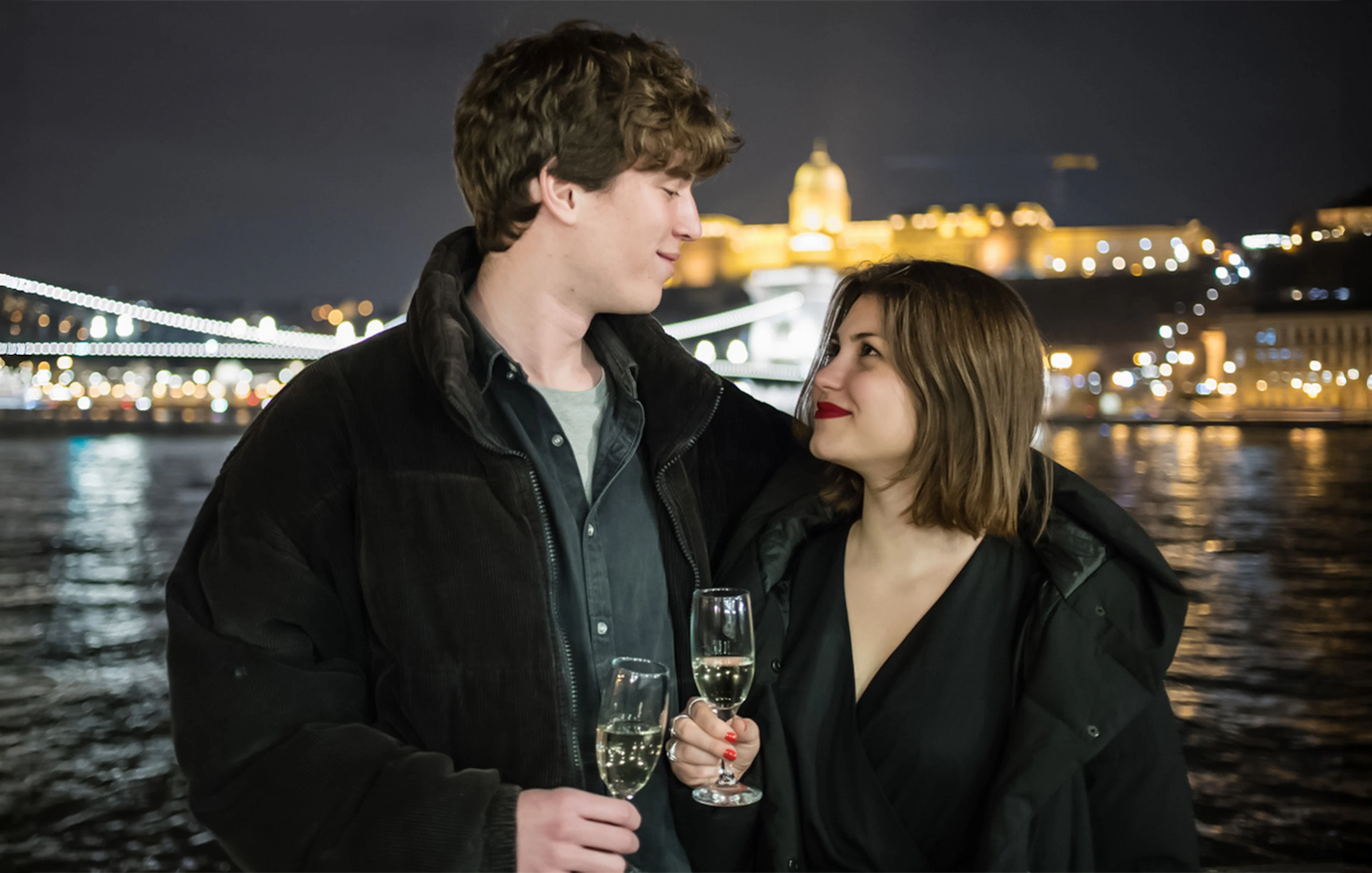 Couple enjoying wine on a Danube River sightseeing dinner cruise at night.