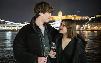Couple enjoying wine on a Danube River sightseeing dinner cruise at night.