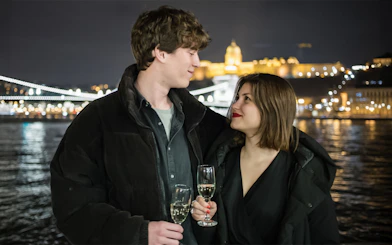 Couple enjoying wine on a Danube River sightseeing dinner cruise at night.