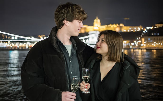 Couple enjoying wine on a Danube River sightseeing dinner cruise at night.