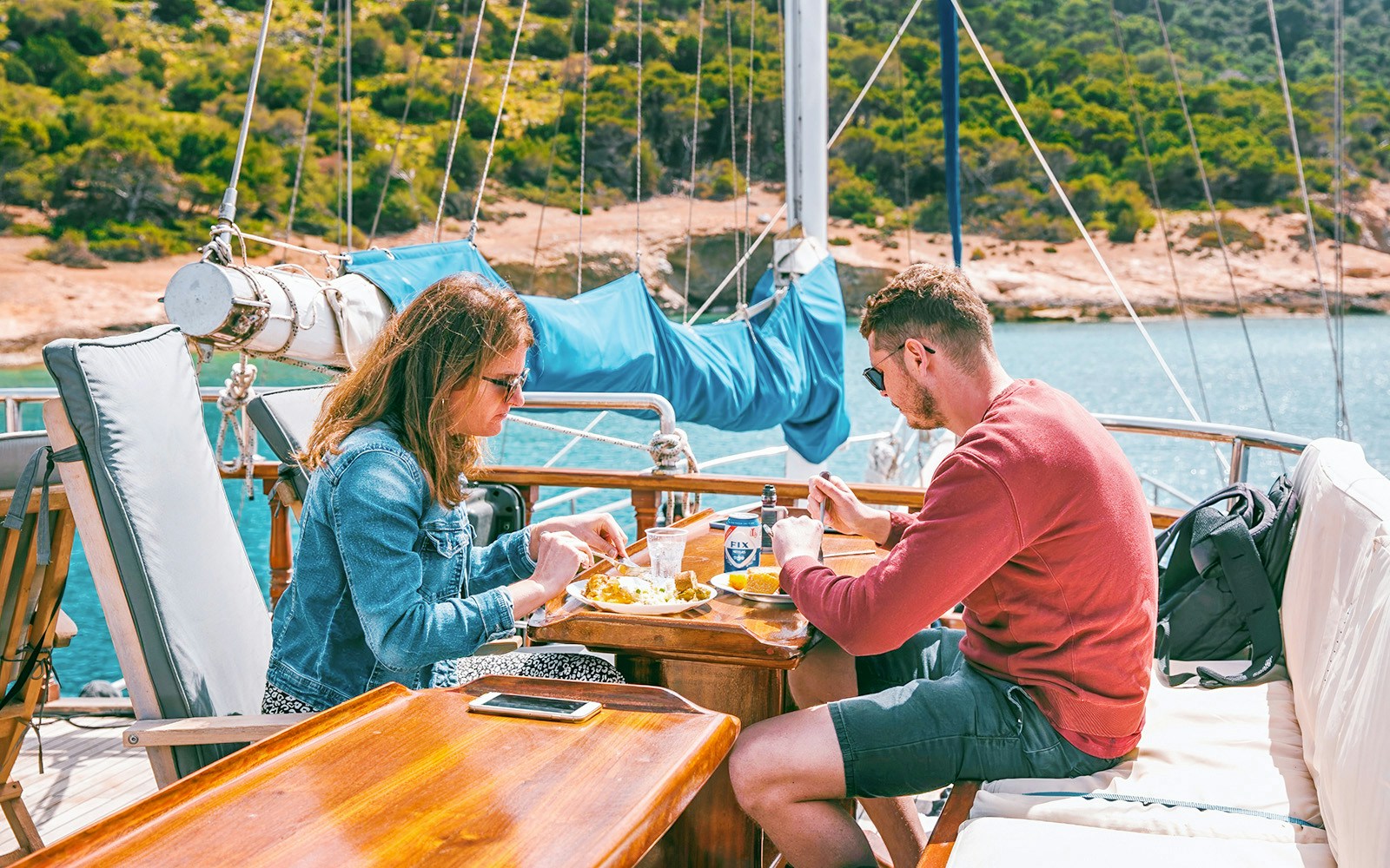 Couples enjoying lunch with beer on a cruise near Agistri, Moni, and Aegina Islands, Greece.