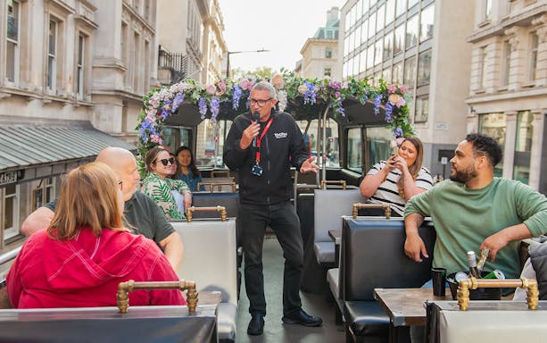 Guide speaking to tourists on a bar bus tour in London.