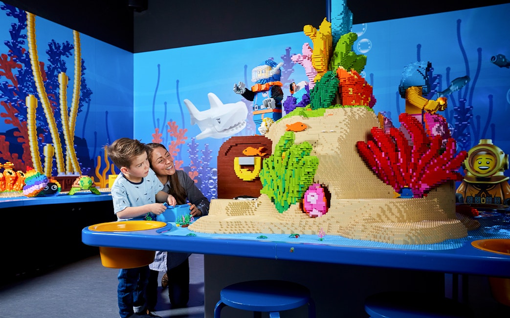 Child and adult exploring LEGO underwater scene at LEGOLAND Discovery Centre.