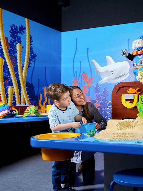 Child and adult exploring LEGO underwater scene at LEGOLAND Discovery Centre.