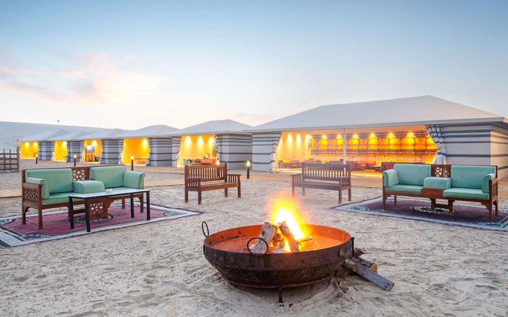 Bonfire at Al Majles Resort with seating and illuminated tents in the background.