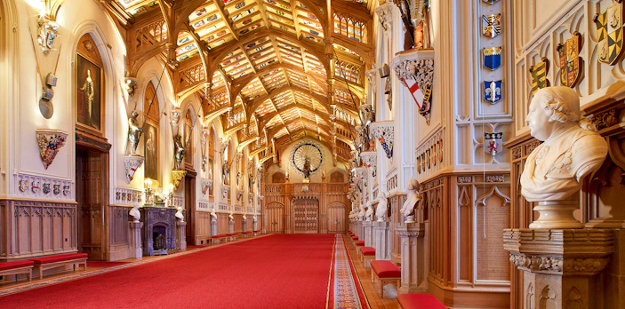 Windsor Castle interior with ornate ceiling, red carpet, and historical busts.
