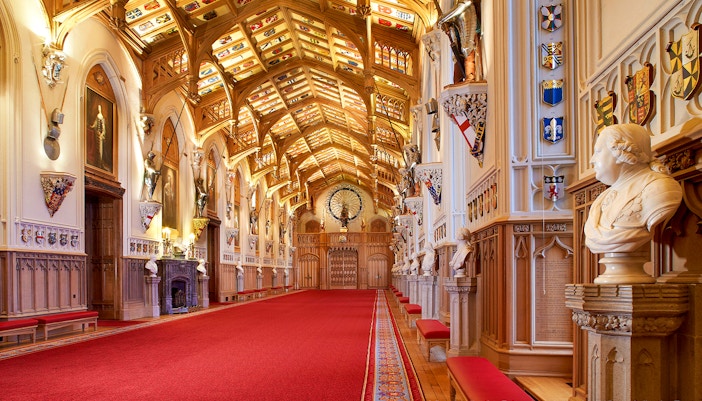 Windsor Castle interior with ornate ceiling, red carpet, and historical busts.