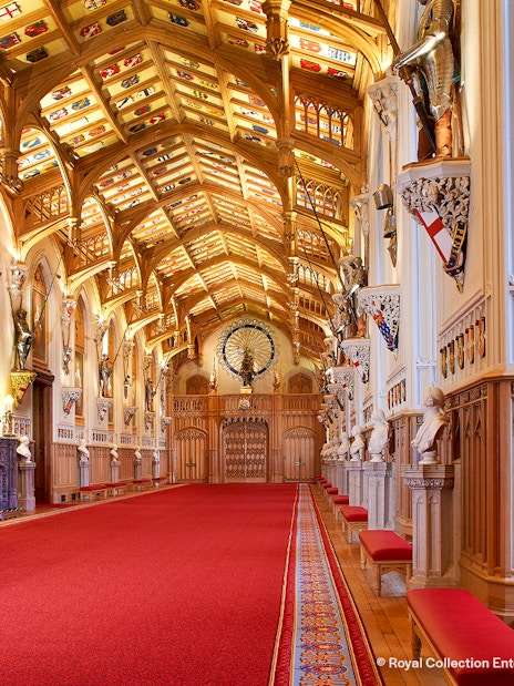 Windsor Castle interior with ornate ceiling, red carpet, and historical busts.