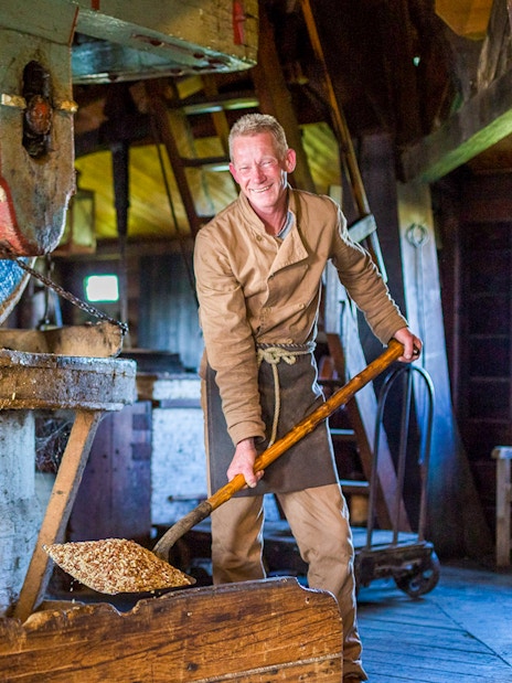 Man working in a traditional Dutch windmill at Zaanse Schans during a full-day tour from Amsterdam.