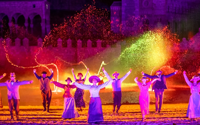 Performers in period costumes dance with colorful lights at The Dream of Toledo Night Show.
