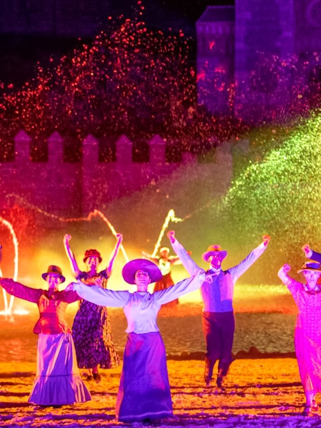 Performers in period costumes dance with colorful lights at The Dream of Toledo Night Show.