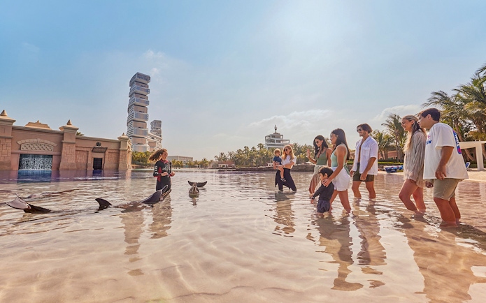 Tourists interacting with dolphins at Atlantis, The Palm, Dubai.