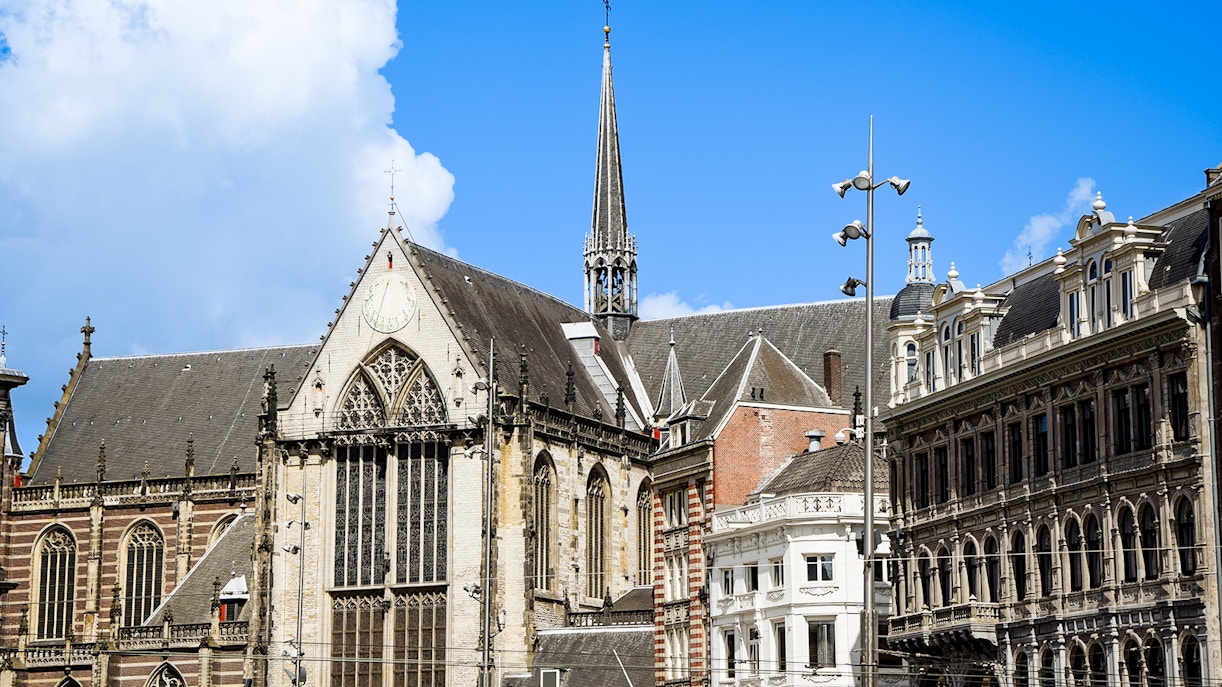 Nieuwe Kerk in Amsterdam with its Gothic architecture and spire against a blue sky.