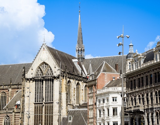 Nieuwe Kerk in Amsterdam with its Gothic architecture and spire against a blue sky.