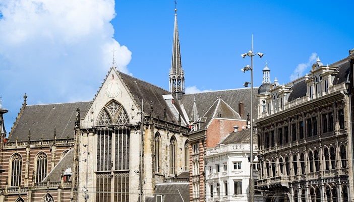 Nieuwe Kerk in Amsterdam with its Gothic architecture and spire against a blue sky.
