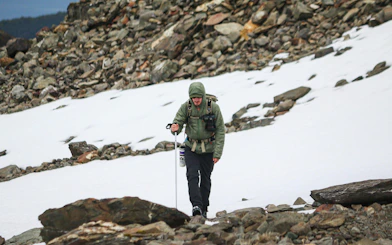 Trekker on rocky path near snowfield, Vinciguerra Glacier, Argentina.