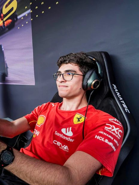 Racer in Ferrari Esports shirt focused on racing simulator setup.