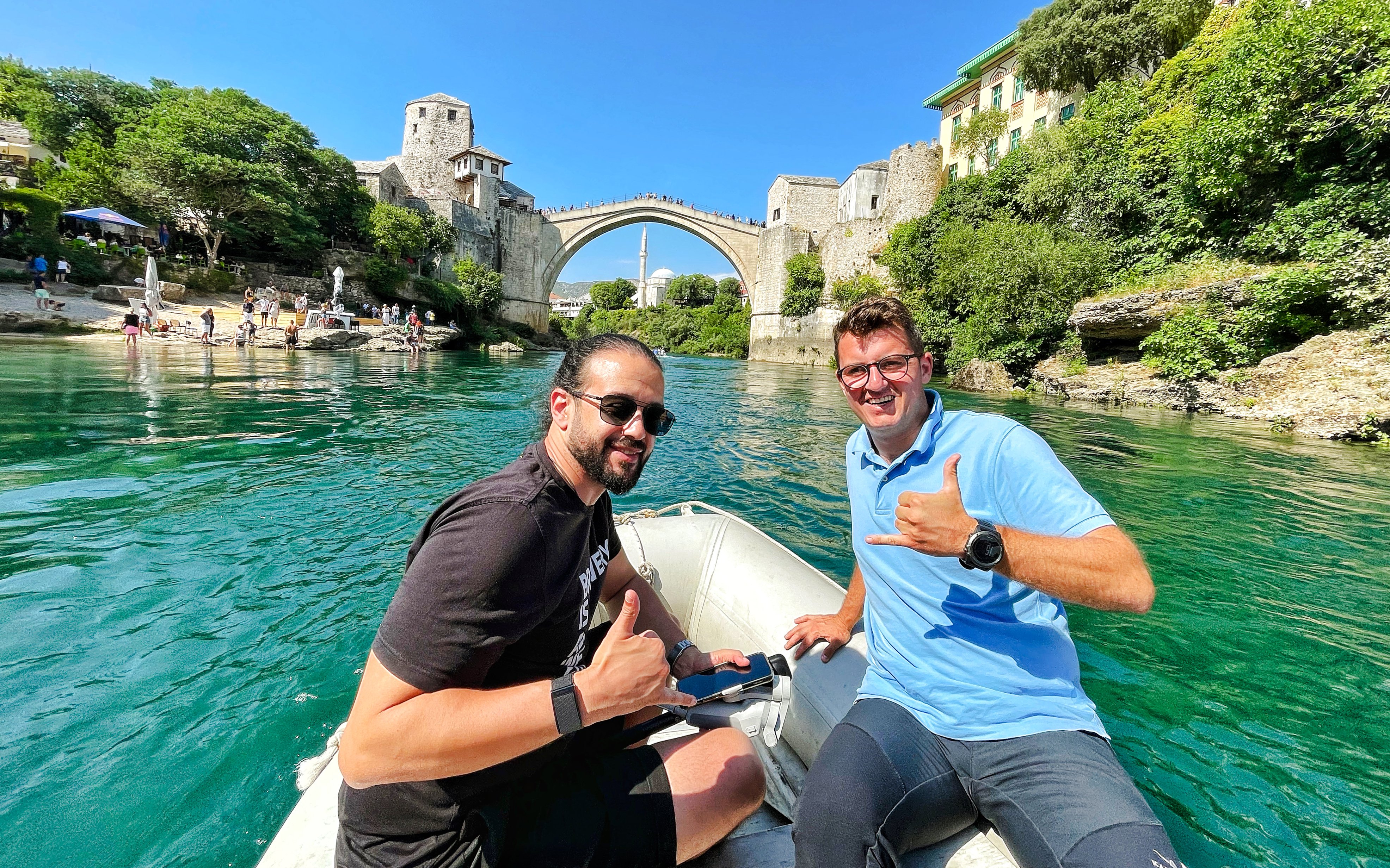 Guests on a boat near Mostar Bridge, Bosnia, with the historic arch in the background.