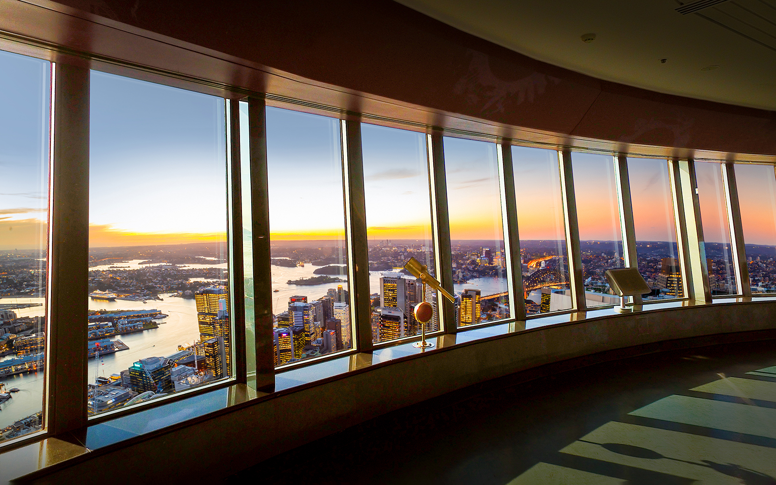 View of Sydney skyline and harbor from observation deck at sunset.