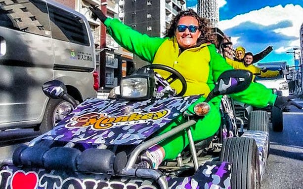 Go-kart riders in colorful outfits driving through Tokyo streets near Skytree.