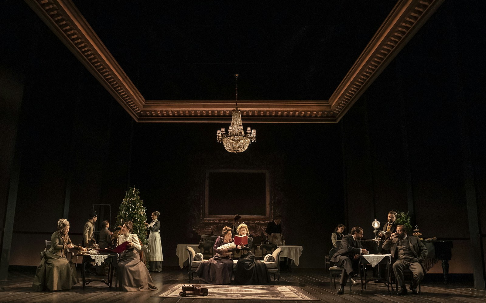 Theater scene from Leopoldstadt with actors in period costumes under a chandelier.