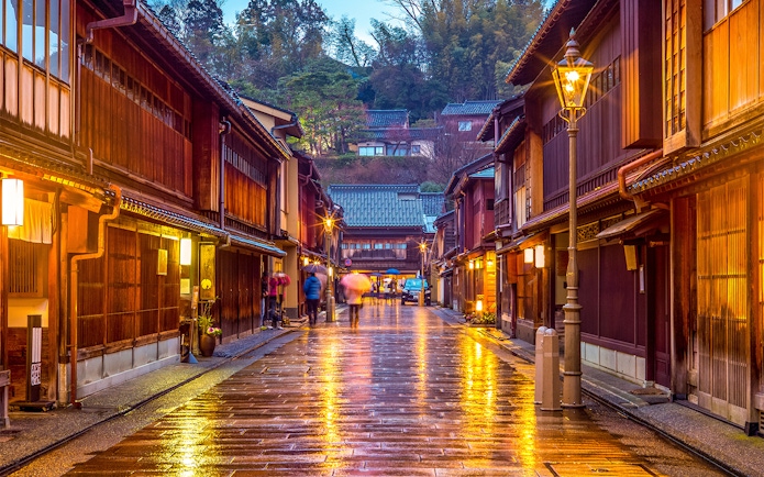 Traditional street in Kanazawa, Japan, with wooden buildings and glowing lanterns, part of Hokuriku Area Pass.