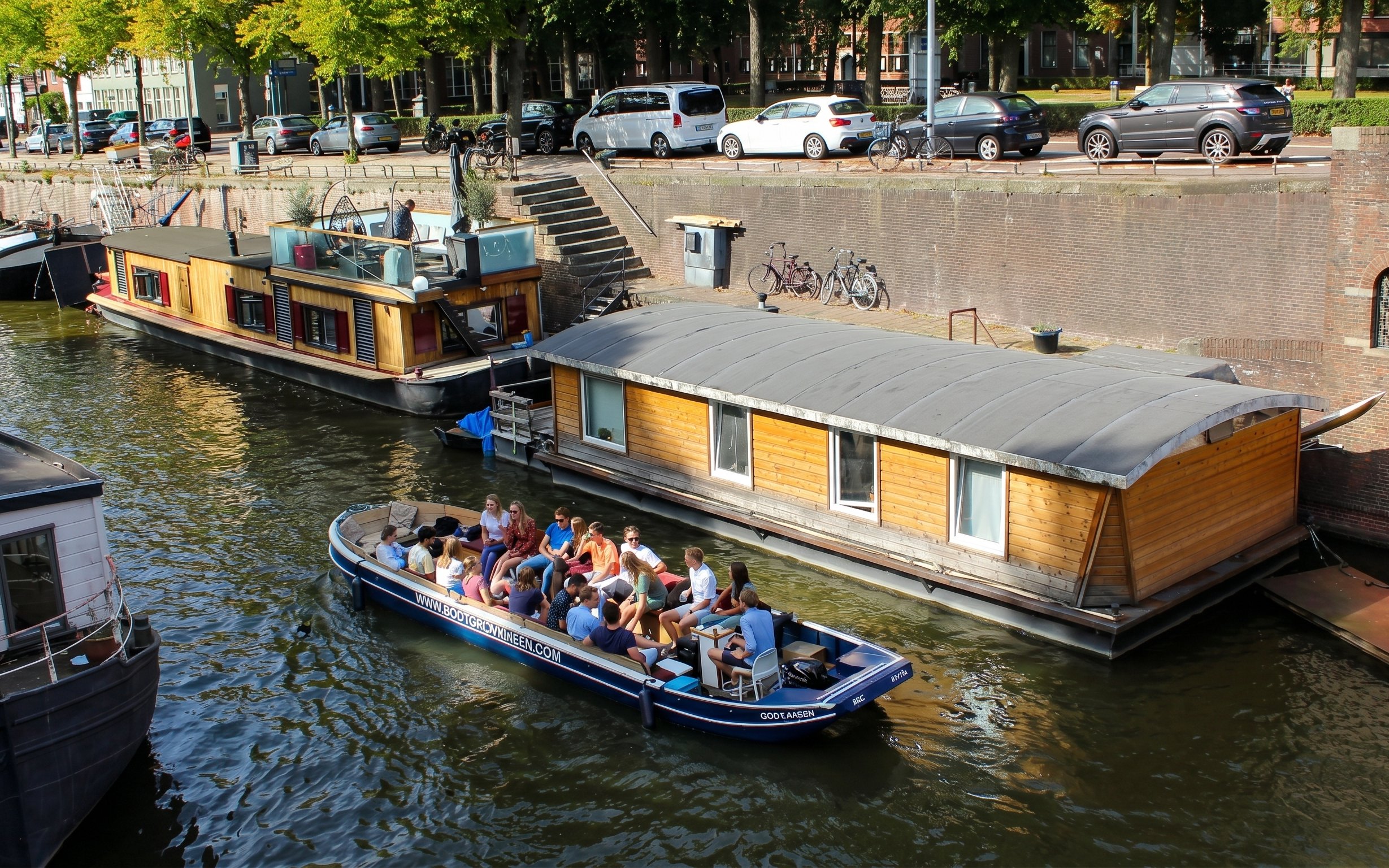 Groningen canal cruise boat with tourists passing houseboats.