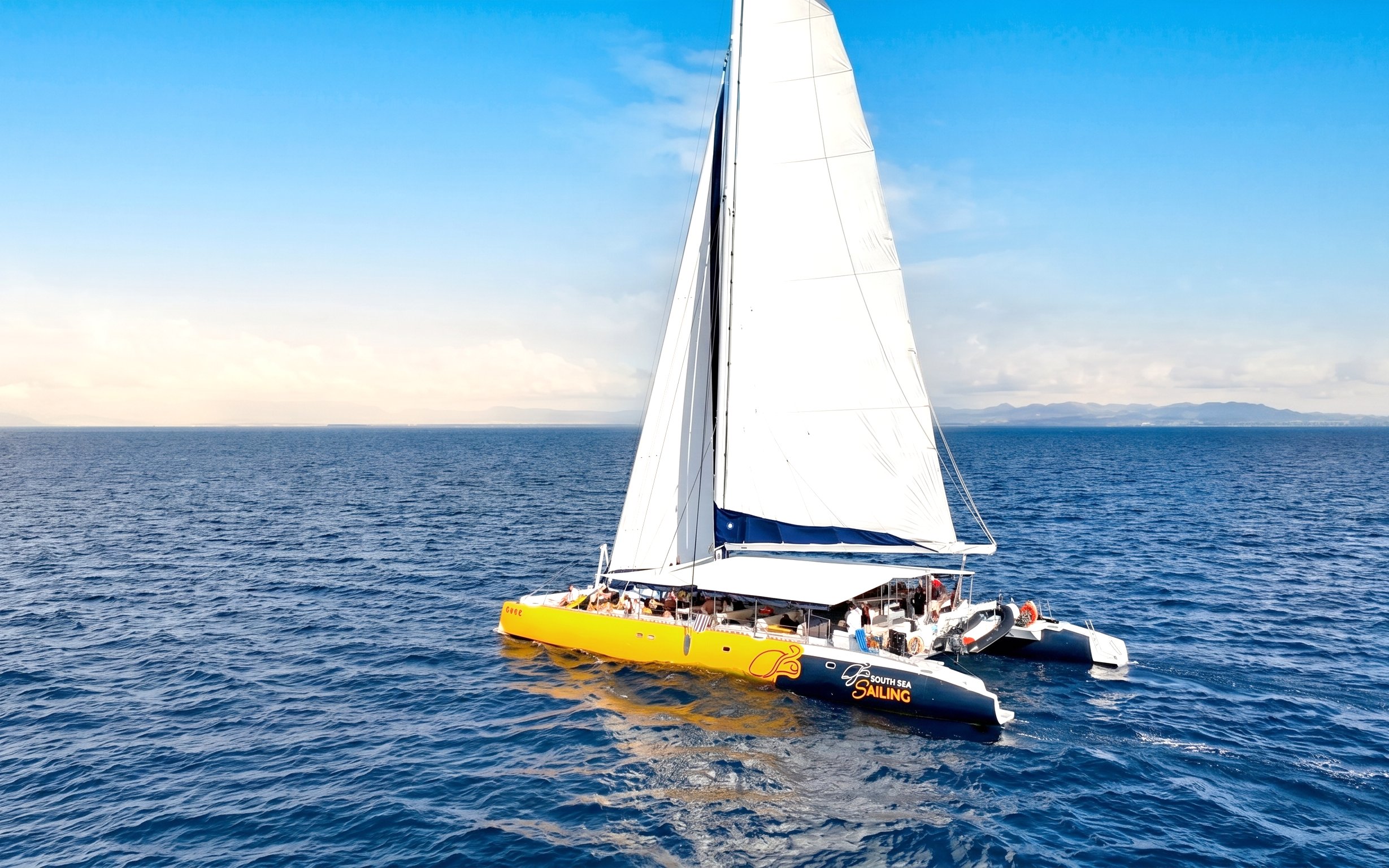 Catamaran sailing on ocean during Sabre Sunset Cruise with BBQ dinner and drinks.