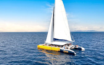 Catamaran sailing on ocean during Sabre Sunset Cruise with BBQ dinner and drinks.