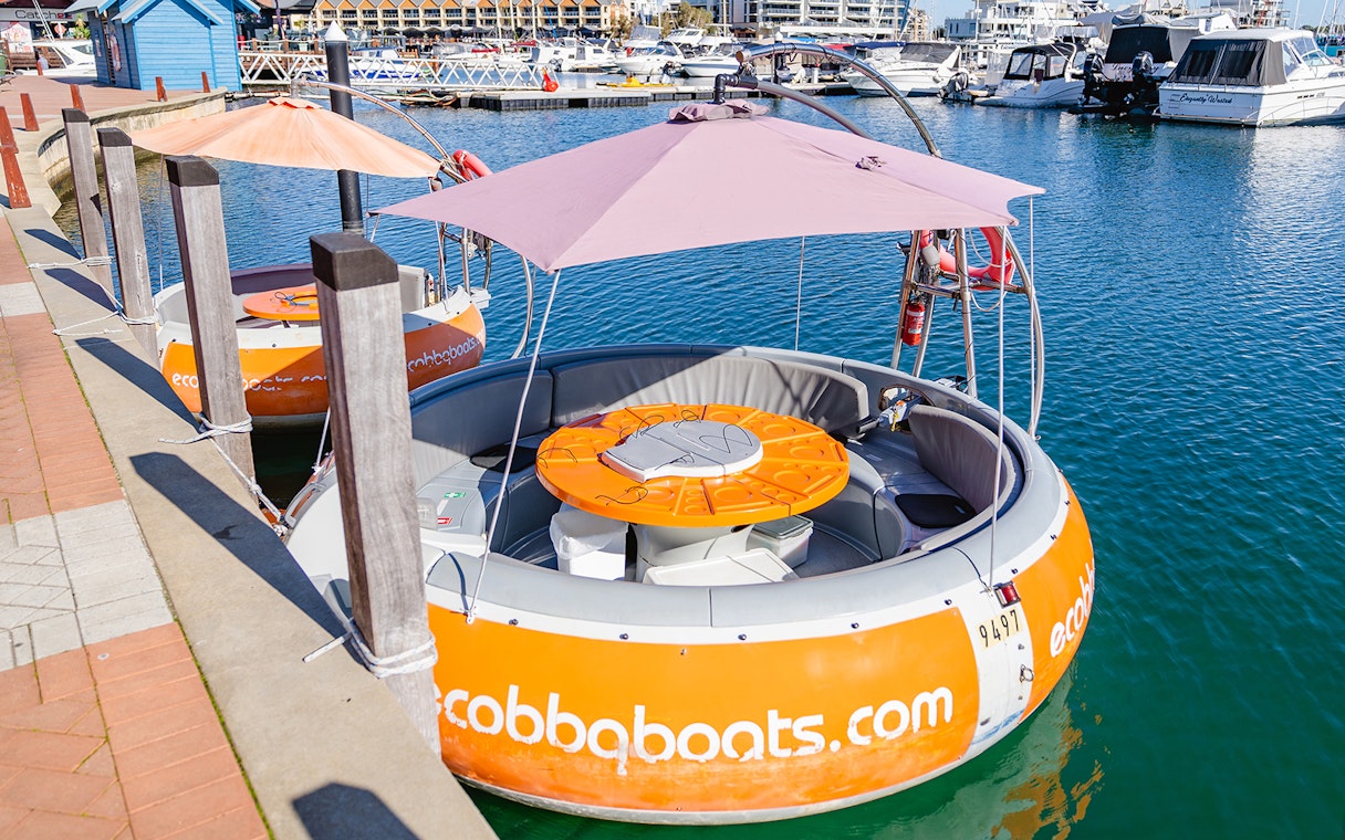Self-drive electric BBQ boat docked in Mandurah marina.