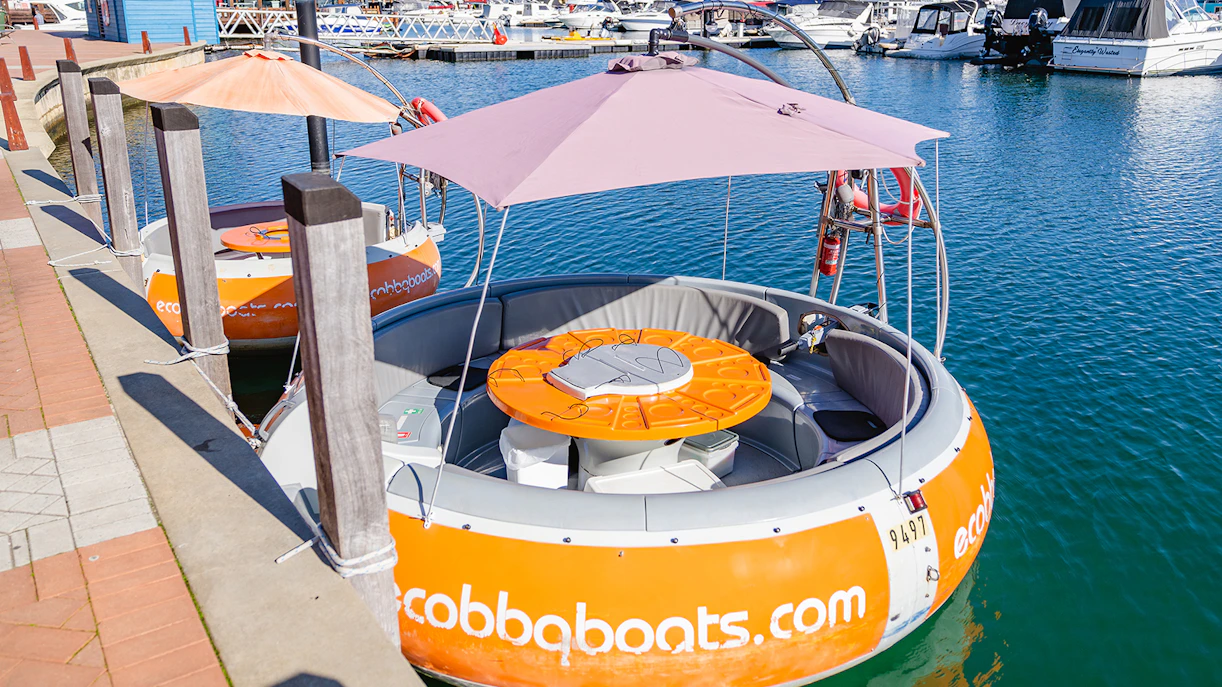 Self-drive electric BBQ boat docked in Mandurah marina.