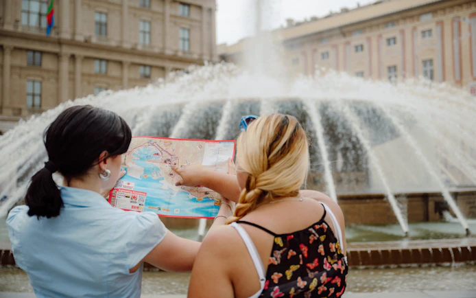 Tourist and guide with map near fountain on Genoa city sightseeing bus tour.