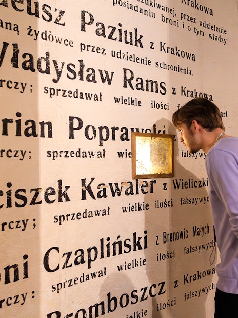 Man examining exhibit wall at Oskar Schindler's Factory museum in Krakow, Poland.