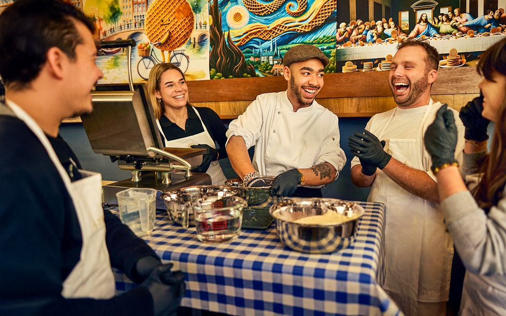 Participants enjoying a Dutch syrup waffle making workshop with a chef in Amsterdam.