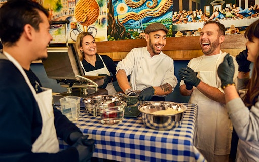 Participants enjoying a Dutch syrup waffle making workshop with a chef in Amsterdam.