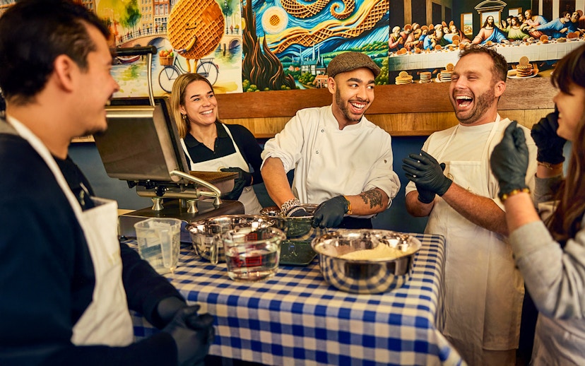 Participants enjoying a Dutch syrup waffle making workshop with a chef in Amsterdam.