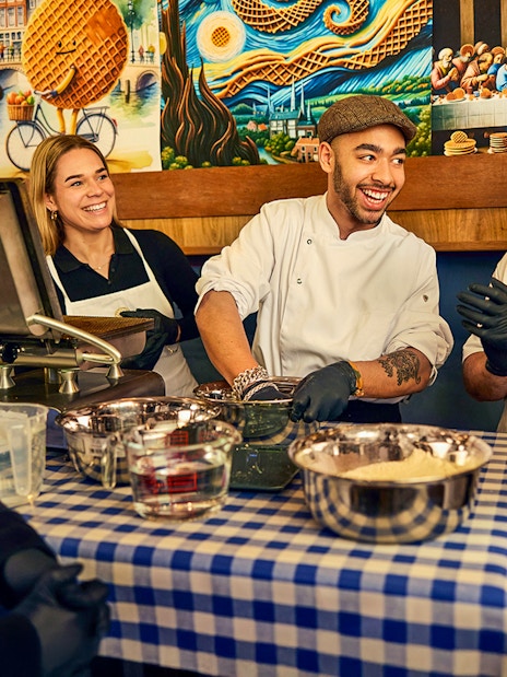 Participants enjoying a Dutch syrup waffle making workshop with a chef in Amsterdam.
