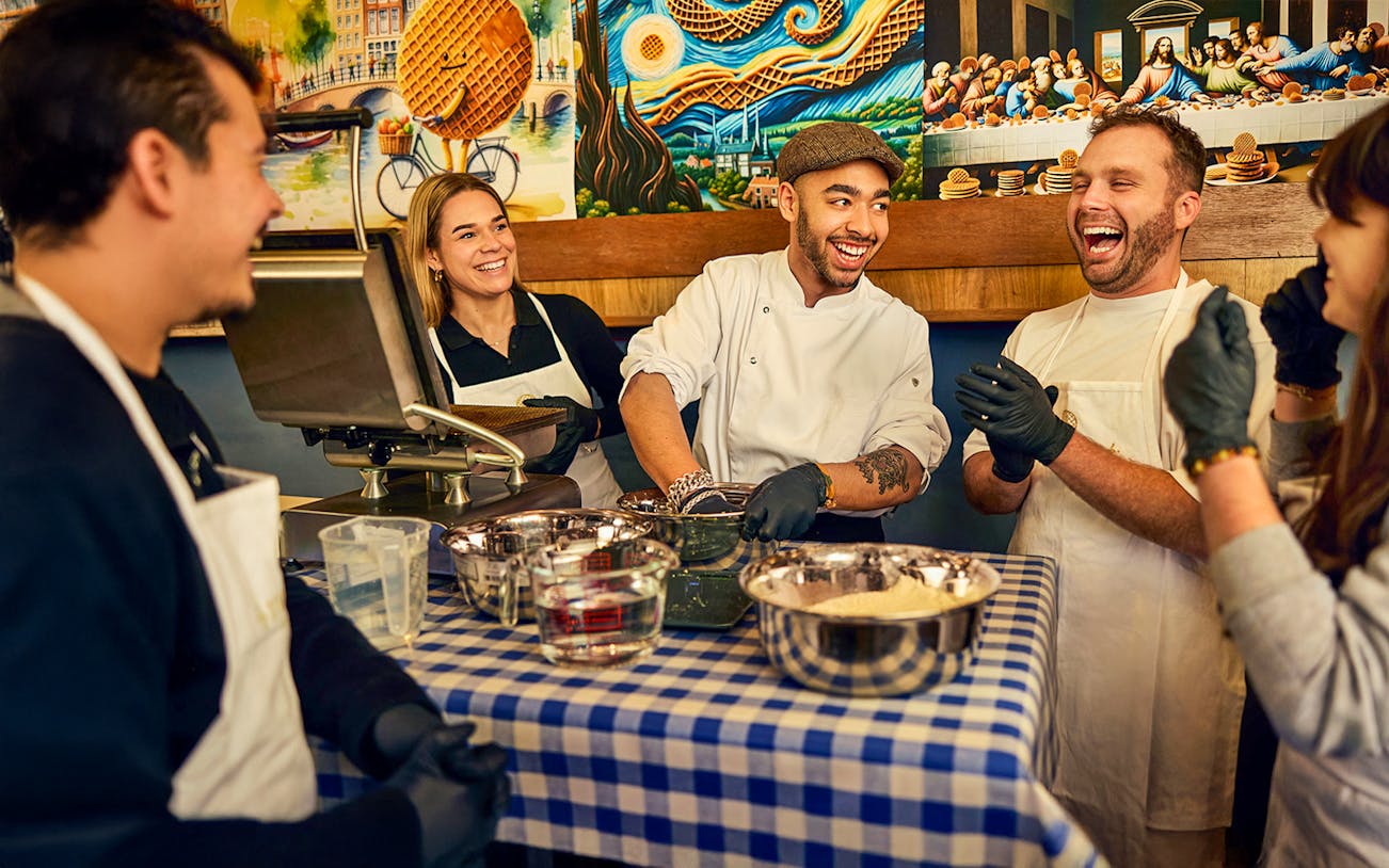 Participants enjoying a Dutch syrup waffle making workshop with a chef in Amsterdam.