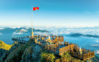 Viewing platform at Sun World Fansipan Legend with Vietnam flag, surrounded by clouds and mountains.