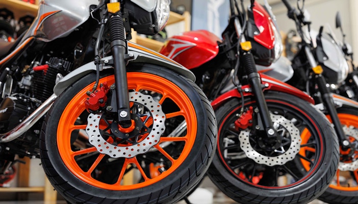 Cyclists exploring booths at Bike Expo New York with Manhattan skyline in background.