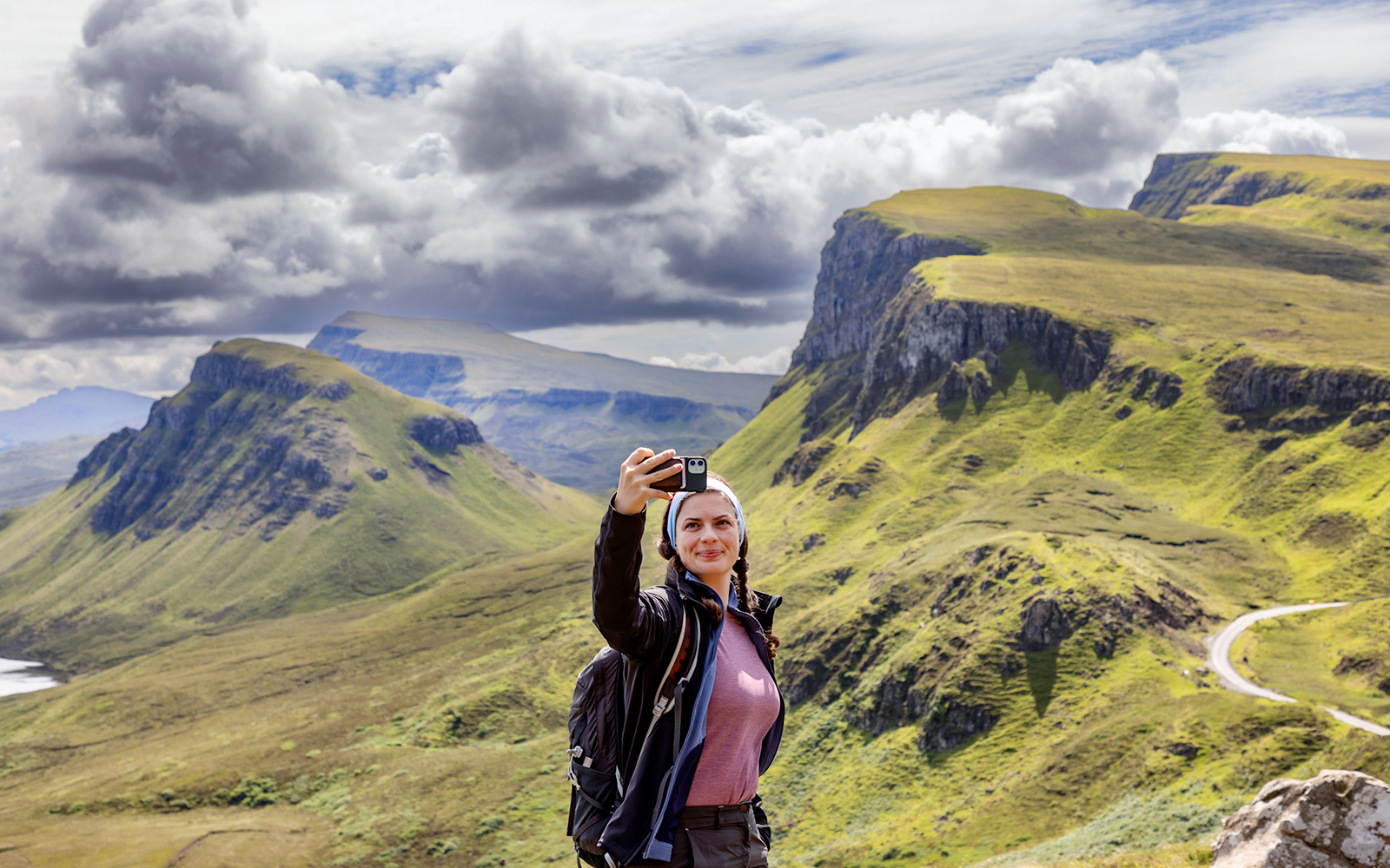 Traveler taking a selfie with the Quiraing mountains in the Isle of Skye, Scotland.