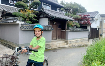 Child on e-bike in front of traditional Japanese house, Asuka Nara tour.